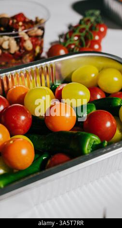 Un plateau de légumes assortis comprenant des tomates, des poivrons et des concombres. Le plateau est argenté et a une variété de couleurs Banque D'Images