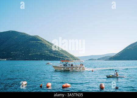 Monténégro, Kotor- 07 juillet 2024 : touriste sur un bateau avec une rame navigue sur la mer devant un yacht d'excursion Banque D'Images