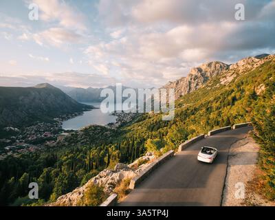 Monténégro, Kotor - 13 juillet 2024 : cabriolet conduit le long d'une route dans les montagnes au-dessus de la baie de Kotor. Monténégro. Drone Banque D'Images