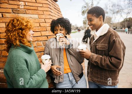 Trois femmes touristes profitent d'une pause café, discutent et rient ensemble pendant leur aventure touristique de la ville Banque D'Images