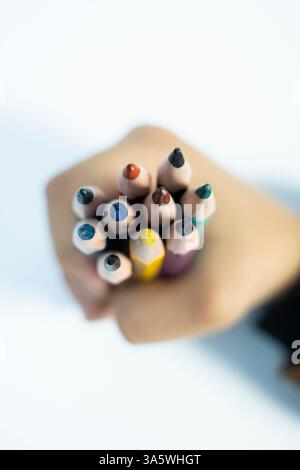 Vue de haut en bas de la couleur de crayon tenue par Kid sur fond blanc. Une image créative à utiliser à des fins d'éduction. Banque D'Images