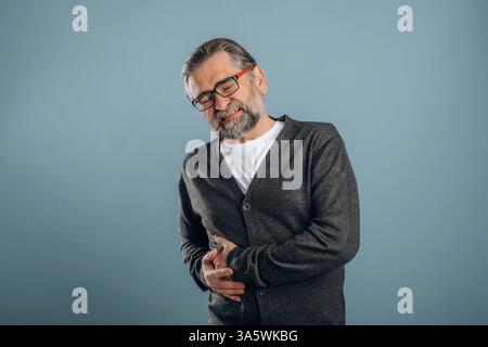 Douleur du côté droit. Homme senior se tient dans le studio sur fond. Banque D'Images