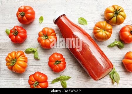 Tomates fraîches, jus de tomate dans une bouteille sur fond blanc Banque D'Images