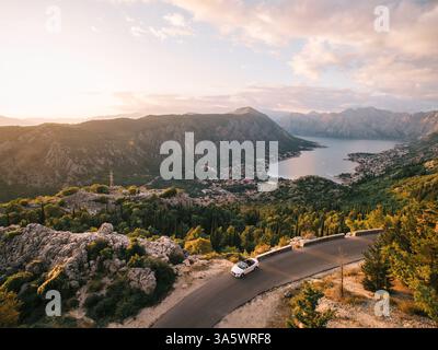 Monténégro, Kotor - 13 juillet 2024 : la voiture roule le long d'une autoroute dans les montagnes au-dessus de la baie de Kotor. Monténégro. Drone Banque D'Images