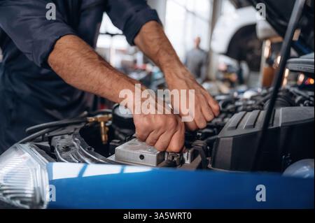Automobile bleue, qui travaille. Vue rapprochée du mécanicien dans la station-service de voiture. Banque D'Images