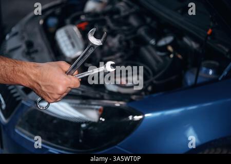 Automobile bleue, qui travaille. Vue rapprochée du mécanicien dans la station-service de voiture. Banque D'Images