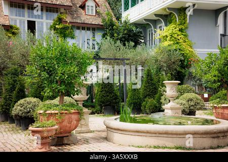 Magnifique jardin paysager avec fontaine sereine, verdure luxuriante et jardinières décoratives. Idéal pour les concepts de design extérieur, tranquillité, an Banque D'Images