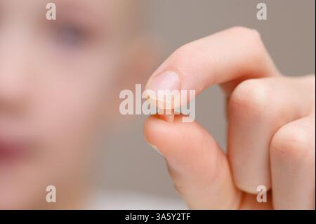 L'enfant tient la dent de bébé tombée dans les mains, gros plan. Les dents de bébé sont remplacées par des dents permanentes. Dentisterie infantile, soins dentaires Banque D'Images