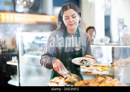 Fille vendeuse travaille dans la boutique de boulangerie cafétéria Banque D'Images
