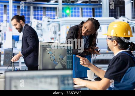 Chef d'équipe de l'installation photovoltaïque supervisant le travail effectué par le technicien pour améliorer la production. Ingénieur d'usine de panneaux solaires montrant le responsable afro-américain identifié des erreurs système Banque D'Images