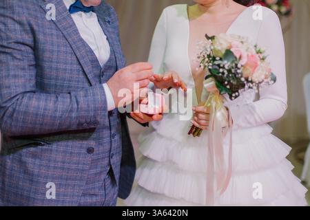 L'échange de jeunes mariés sonne, le marié met l'anneau sur la mariée en mariage civil Banque D'Images