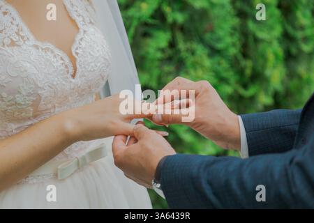Beau jeune marié met sur bague à la mariée le jour du mariage, ils sont heureux ensemble Banque D'Images