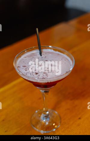 Cocktail rouge avec verre à cocktail en mousse blanche avec un tube de boisson alcoolisée. gros plan Banque D'Images