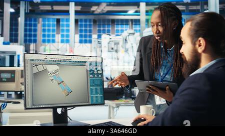 Responsable d'usine photovoltaïque et collègue brainstorming, ajustant les paramètres du système pour maximiser la production d'énergie. Homme parlant avec un collègue, optimisant l'approvisionnement en énergie dans l'usine de panneaux solaires, caméra A. Banque D'Images
