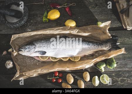 La préparation de poisson saumon entier pour la cuisine. Des légumes sur la table. Style Vintage Banque D'Images