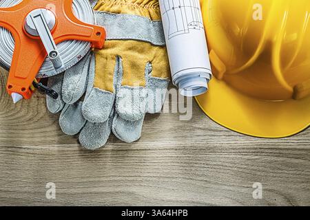 Bleus roulés gants de sécurité ruban de mesure casque de construction sur planche de bois Banque D'Images