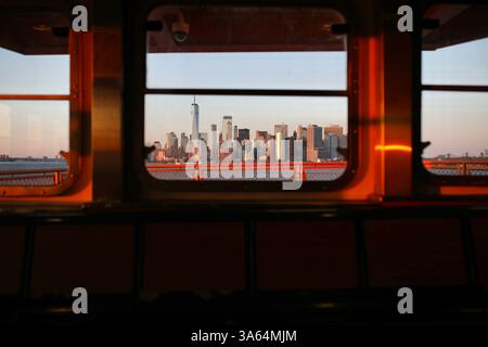 New York, États-Unis. 21 mars 2025. Horizon de Manhattan vu au coucher du soleil depuis le ferry de Staten Island. Le ferry de Staten Island est un ferry gratuit reliant Manhattan au quartier de Staten Island à New York. Le trajet de 25 minutes est assuré par le Département des Transports de la ville de New York. Crédit : SOPA images Limited/Alamy Live News Banque D'Images