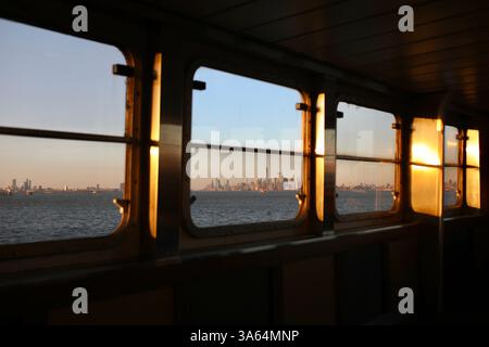 New York, États-Unis. 21 mars 2025. Horizon de Manhattan vu au coucher du soleil depuis le ferry de Staten Island. Le ferry de Staten Island est un ferry gratuit reliant Manhattan au quartier de Staten Island à New York. Le trajet de 25 minutes est assuré par le Département des Transports de la ville de New York. (Photo par Apolline Guillerot-Malick/SOPA images/Sipa USA) crédit : Sipa USA/Alamy Live News Banque D'Images