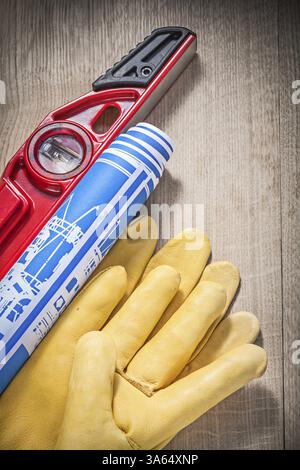 Composition des gants de sécurité niveau de construction bleu roulé dessins d'ingénierie sur planche de bois Banque D'Images