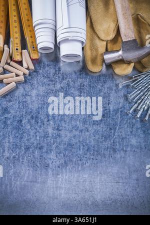 Blueprint Rolls griffes Hammer gants de sécurité en bois mètres clous en acier et chevilles sur le concept de construction de fond métallique rayé Banque D'Images