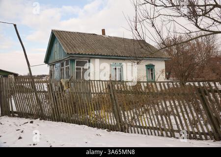 Vieille maison abandonnée dans un village ukrainien avec une vieille clôture penchée en bois. Banque D'Images
