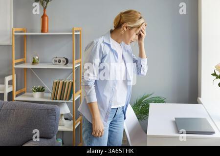 Femme adulte surmenée souffrant de maux de tête sévères ou de migraine, touchant le front Banque D'Images