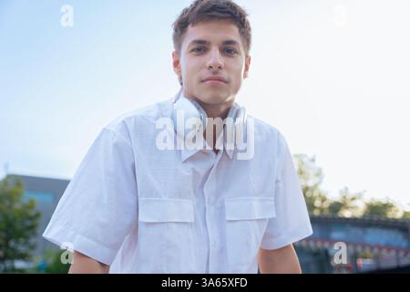 Homme caucasien confiant avec des écouteurs regardant la caméra dans un cadre extérieur Banque D'Images