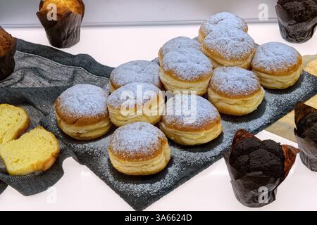 Beignets berlinois frais et muffins sur la table dans le café, vue de dessus. Pâtisseries fraîches diverses dans la vitrine de boulangerie. Banque D'Images