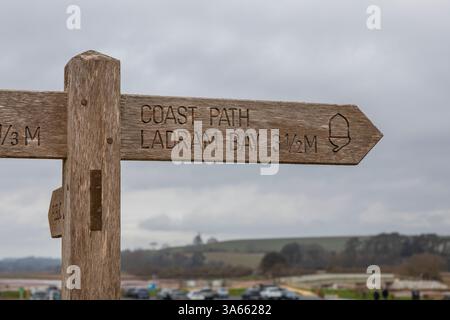 Un panneau de chemin côtier pointant vers la baie de Ladram sur la plage de Budleigh Salterton dans le Devon. Banque D'Images