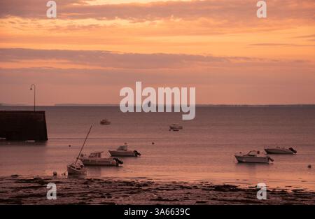 Cancale (Bretagne) au coucher du soleil. Amarre des voiliers et vue sur la silhouette rêveuse du Mont Saint Michel à l'horizon. Banque D'Images