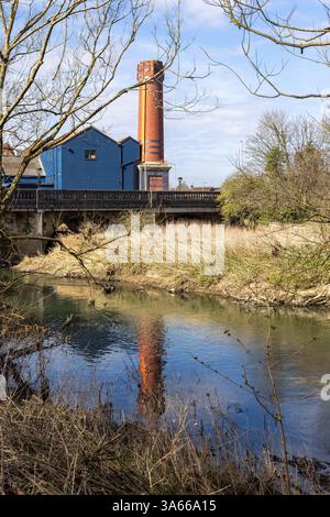 Reflets dans la rivière Avon d'une grande cheminée en briques rouges utilisée pour la condensery de l'ancienne crémerie, Avonside, Melksham, Wiltshire, Angleterre, ROYAUME-UNI Banque D'Images