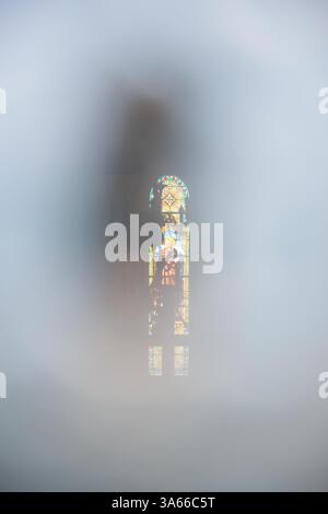 BRETAGNE, FRANCE - 4 AOÛT 2018 : vitrail avec Saint François d'assise vu à travers le trou de serrure dans la porte fermée de l'église. Fond mystique Banque D'Images