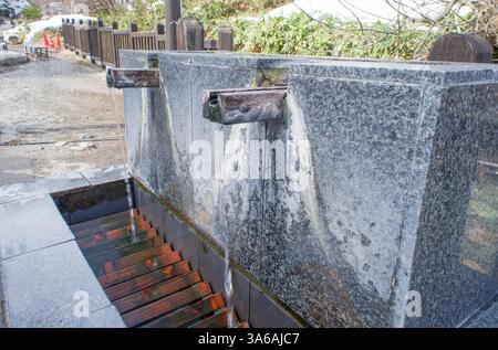 Une fontaine d'eau chaude en pierre au pied du parc Sainokawara, à Kusatsu Onsen, Gunma, Japon. Banque D'Images