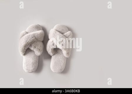 Paire de chaussons féminins gris doux pour la maison sur fond gris. Vue de dessus. Copier l'espace. Banque D'Images