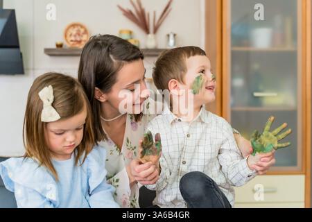 Maman et enfants dans la cuisine peignant leurs mains. Du temps en famille ensemble Banque D'Images