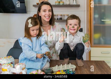 Mère et enfants coloriant les œufs de Pâques dans la cuisine. Veille de Pâques, printemps Banque D'Images