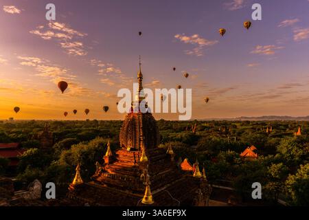 Vue panoramique de montgolfières volant au-dessus d'anciennes pagodes bouddhistes et temples au coucher du soleil, zone archaelogical Bagan, région de Mandalay, Myanmar (Birmanie) K. Banque D'Images