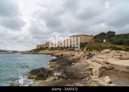 Gzira, Malte - 11 avril 2021 : les gens sur la rive de l'île de Manoel dans le port de Marsamxett. En arrière-plan se trouve Fort Manoel, un fort étoilé du 18ème siècle. Banque D'Images