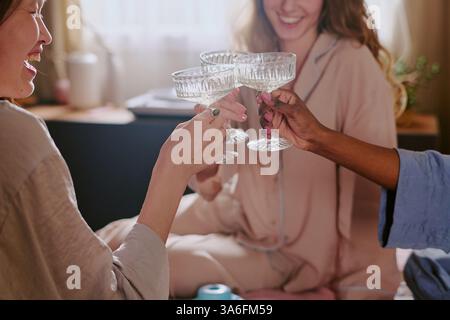 Gros plan moyen de trois verres en cristal poli dans la main d'amis biraciaux, ils apprécient boire du champagne et avoir du temps libre ensemble Banque D'Images