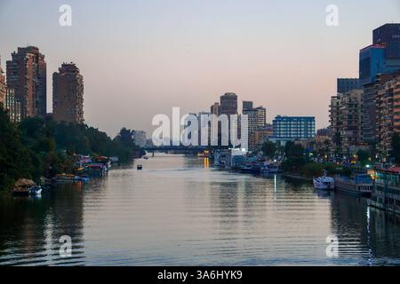 Vue panoramique sur le Nil au Caire en Égypte depuis un pont montrant des bateaux se déplaçant à travers l'eau et une ligne d'horizon urbaine au loin Banque D'Images
