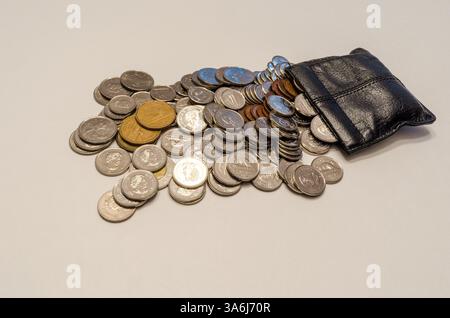 Pile de pièces assorties semblant déborder d'une pochette à langer en cuir noir Banque D'Images