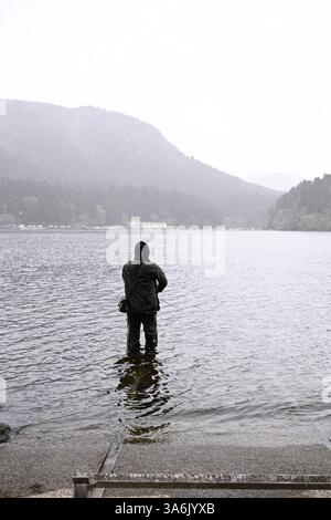 Pêcheur solitaire debout dans le lac Ashi, Hakone, Japon, par une journée brumeuse – scène paisible et contemplative Banque D'Images
