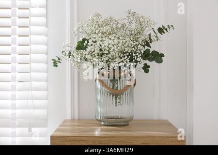 Belles fleurs de gypsophila et branches d'eucalyptus en vase sur table à la maison Banque D'Images