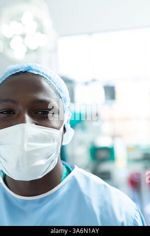 Professionnel de santé souriant portant un masque et des gommages dans la salle d'opération de l'hôpital Banque D'Images