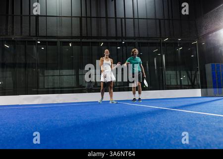 Jouer au padel tennis sur le court, double joueurs souriant et détendu pendant le match, espace copie Banque D'Images