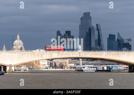 Bus rouge traversant Waterloo Bridge sur la Tamise avec la ville de Londres vue depuis Victoria Embankment, Londres, Angleterre, Royaume-Uni Banque D'Images