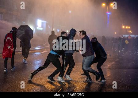 Ankara, Turquie. 26 mars 2025. Un groupe de policiers en civil détient un manifestant pendant l'intervention du canon à eau. Les manifestations qui ont commencé après l'arrestation du maire métropolitain d'Istanbul, Ekrem Imamoglu, du Parti républicain du peuple (CHP), le 23 mars, se poursuivent dimanche. La police a empêché la marche de la messe réunie sur la place K ?z ?Lay et l'Université du moyen-Orient (ODTU) à Ankara. (Photo de Tunahan Turhan/SOPA images/Sipa USA) crédit : Sipa USA/Alamy Live News Banque D'Images