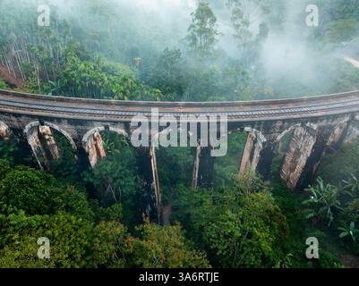L'emblématique pont Nine Arch près d'Ella, au Sri Lanka, émerge de la brume, entouré d'une jungle tropicale luxuriante, mettant en valeur un mélange d'histoire, de nature, d'an Banque D'Images