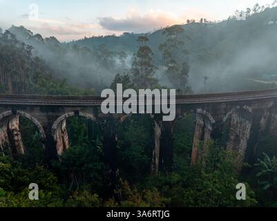 L'emblématique pont Nine Arch près d'Ella, au Sri Lanka, émerge de la brume, entouré d'une jungle tropicale luxuriante, mettant en valeur un mélange d'histoire, de nature, d'an Banque D'Images