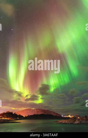 Belle Aurora Borealis sur la maison sur l'île de Kvaløya, dansant les aurores boréales avec la lumière verte, les grèves rouges et violettes, les rayons colorés clairs Banque D'Images